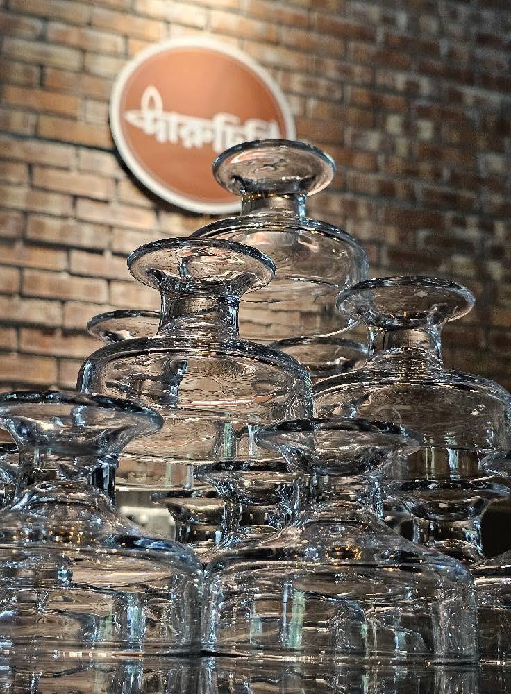 Stacked glasses in front of the Daruchini logo on a brick wall